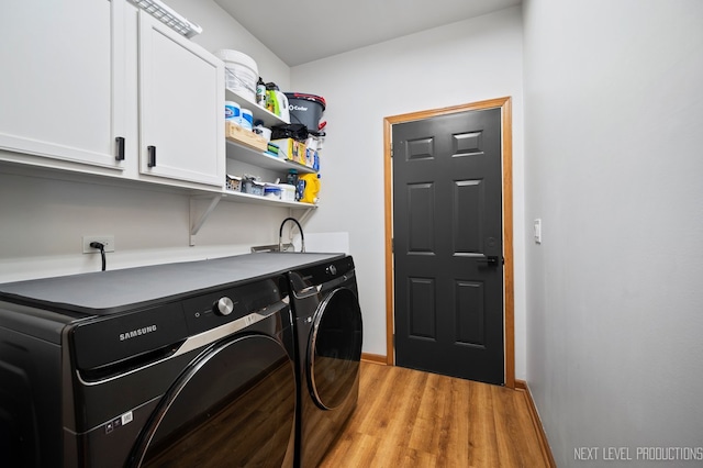 laundry area with light hardwood / wood-style floors, washing machine and dryer, and cabinets