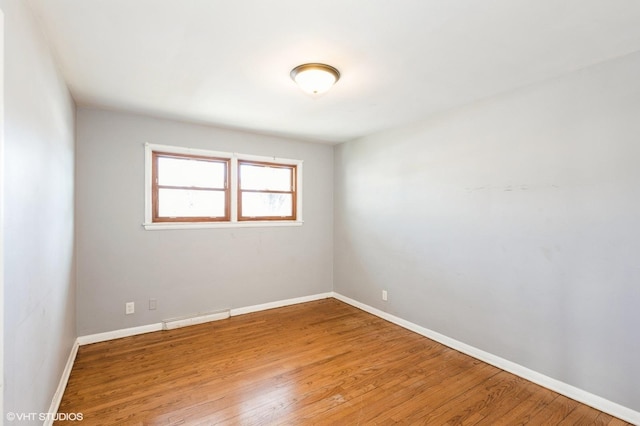 unfurnished room featuring a baseboard heating unit and hardwood / wood-style flooring