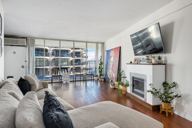 living room featuring a wall of windows, a wall mounted AC, and dark wood-type flooring