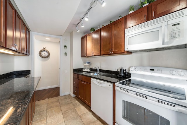 kitchen featuring sink, white appliances, and dark stone countertops