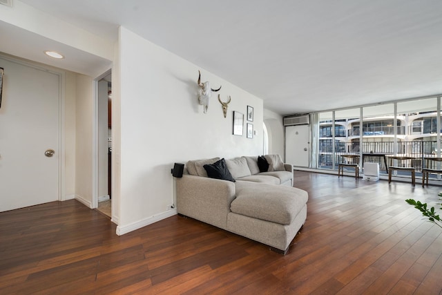 living room featuring dark wood-type flooring, expansive windows, and a wall mounted AC