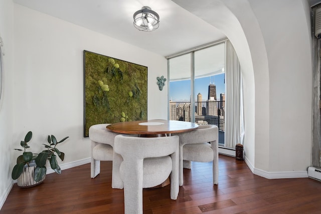 dining space featuring floor to ceiling windows, a baseboard heating unit, and dark hardwood / wood-style floors