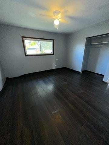 unfurnished bedroom with a closet, dark hardwood / wood-style floors, and ceiling fan