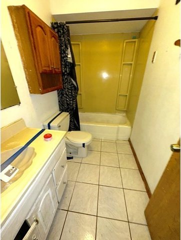 full bathroom featuring toilet, vanity, shower / bath combo, and tile patterned flooring