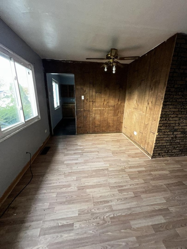 spare room featuring ceiling fan, wood walls, and light hardwood / wood-style flooring