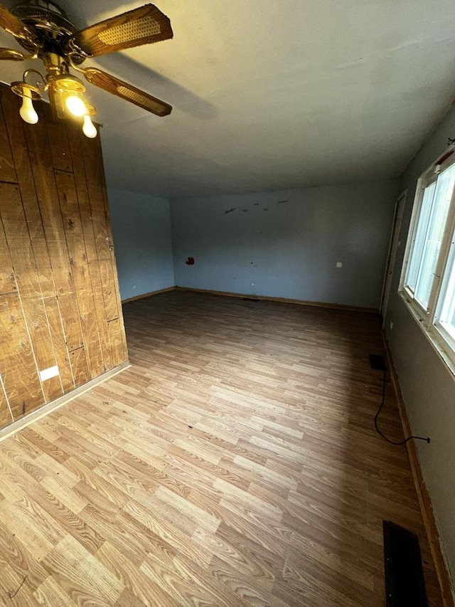 interior space featuring ceiling fan, wood walls, and light hardwood / wood-style floors