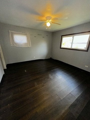 unfurnished room with ceiling fan and dark wood-type flooring