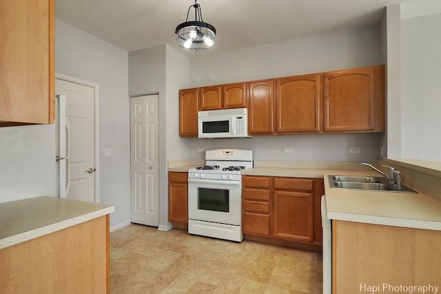 kitchen featuring light countertops, white appliances, a sink, and pendant lighting