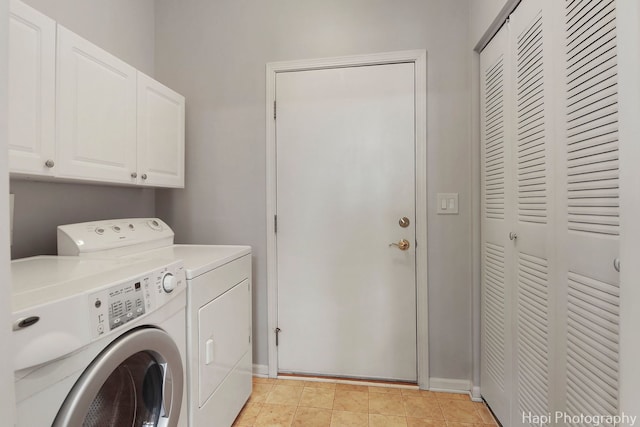 laundry area with light tile patterned floors, separate washer and dryer, cabinet space, and baseboards