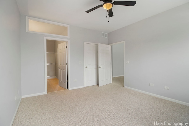 unfurnished bedroom featuring ceiling fan, connected bathroom, light colored carpet, visible vents, and baseboards