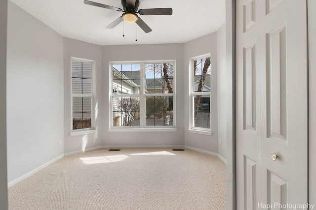 carpeted spare room with ceiling fan, visible vents, and baseboards