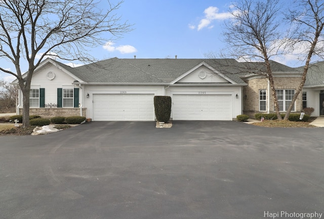 view of front of house with aphalt driveway, roof with shingles, and a garage