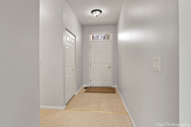 doorway with baseboards and carpet flooring