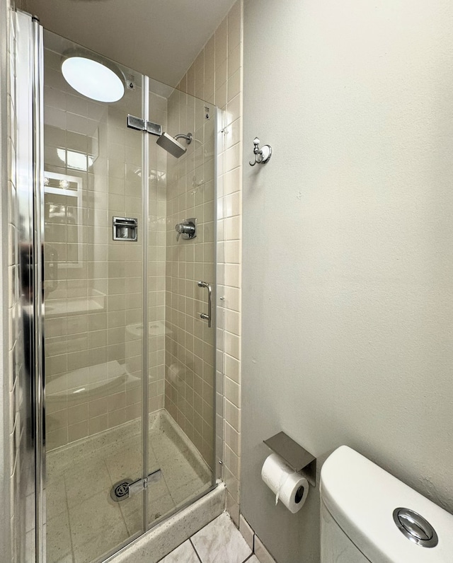 bathroom featuring an enclosed shower, tile patterned flooring, and toilet