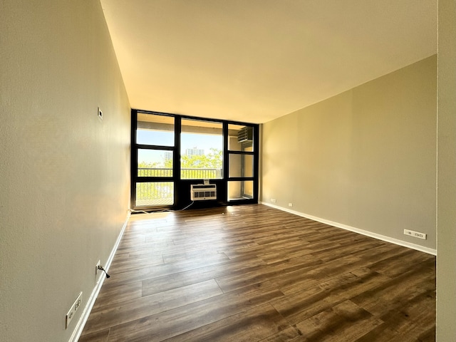 empty room featuring dark hardwood / wood-style flooring, a wall of windows, and a wall mounted AC