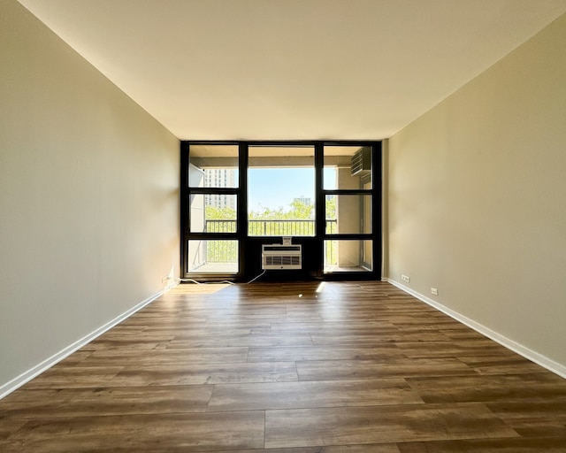 unfurnished room featuring dark wood-type flooring, a wall of windows, and a wall unit AC