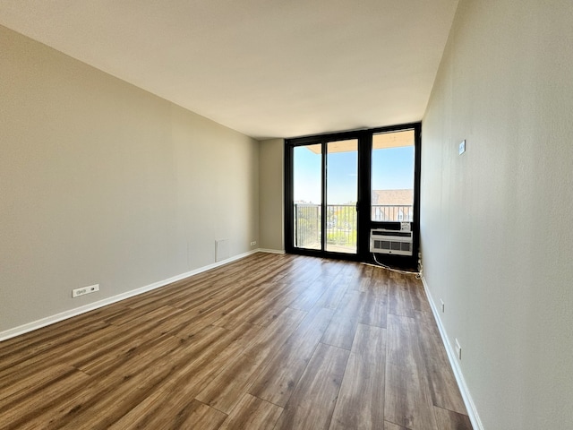 spare room with hardwood / wood-style flooring, a wall unit AC, and floor to ceiling windows