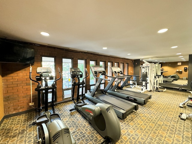 exercise room featuring brick wall and carpet floors