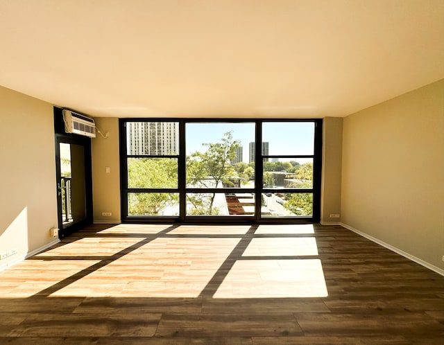 empty room featuring wood-type flooring, floor to ceiling windows, and a wall unit AC