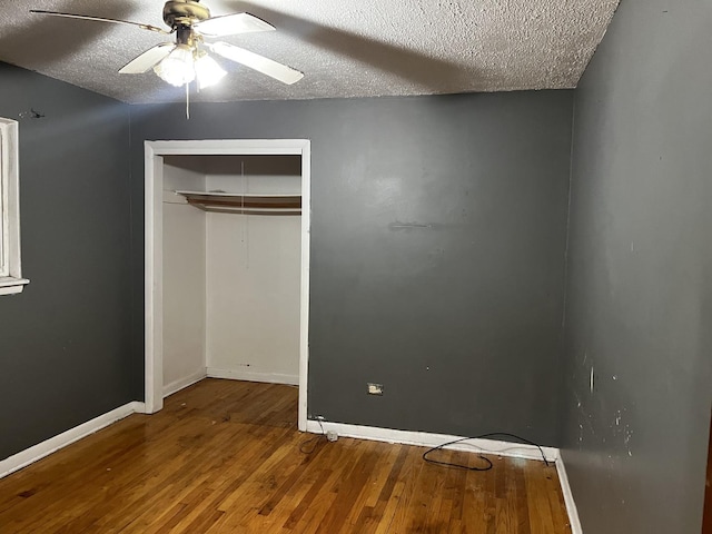 unfurnished bedroom with a closet, ceiling fan, hardwood / wood-style floors, and a textured ceiling