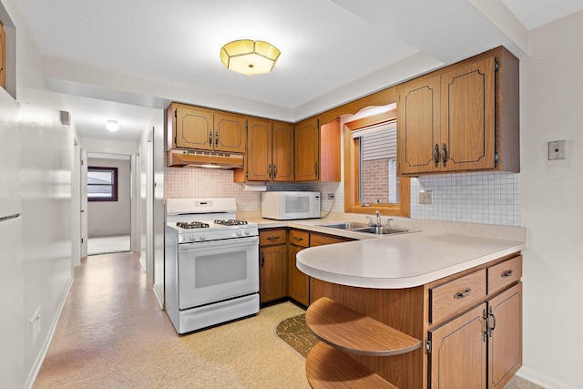 kitchen with sink, white appliances, kitchen peninsula, and decorative backsplash