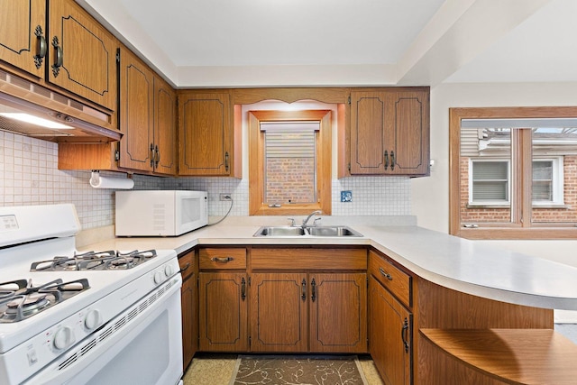 kitchen featuring sink, white appliances, kitchen peninsula, and decorative backsplash