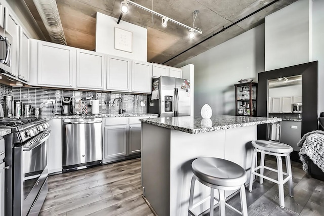 kitchen with decorative backsplash, stainless steel appliances, a kitchen breakfast bar, and a kitchen island