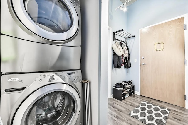 laundry area featuring stacked washing maching and dryer and light wood-type flooring