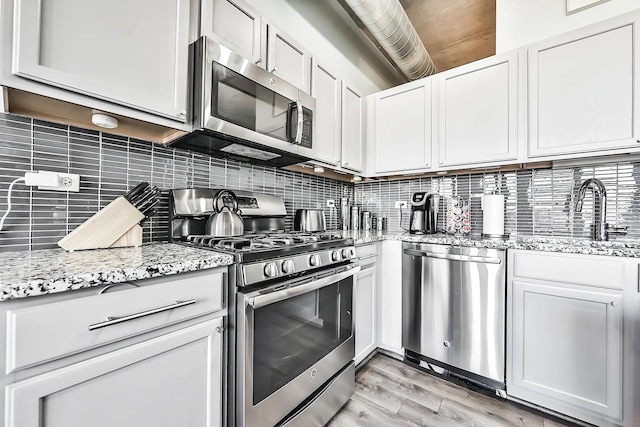 kitchen with backsplash, appliances with stainless steel finishes, sink, and white cabinets