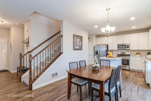 dining area with an inviting chandelier and light hardwood / wood-style flooring