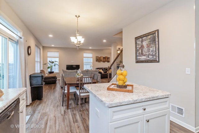 kitchen with decorative light fixtures, white cabinetry, dishwashing machine, a center island, and light wood-type flooring