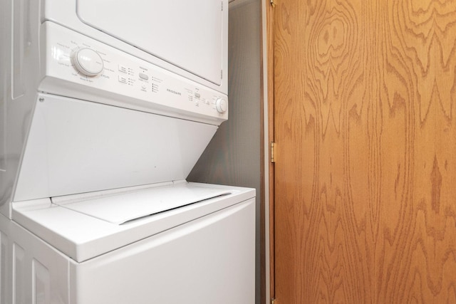 clothes washing area with stacked washing maching and dryer