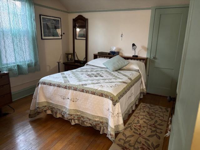 bedroom with wood-type flooring and vaulted ceiling