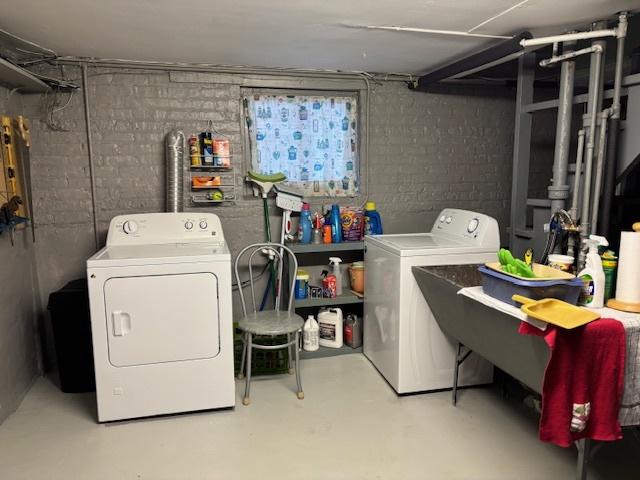 washroom featuring brick wall and washer and dryer