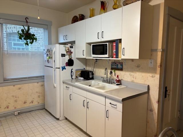 kitchen featuring white cabinetry, sink, and white appliances