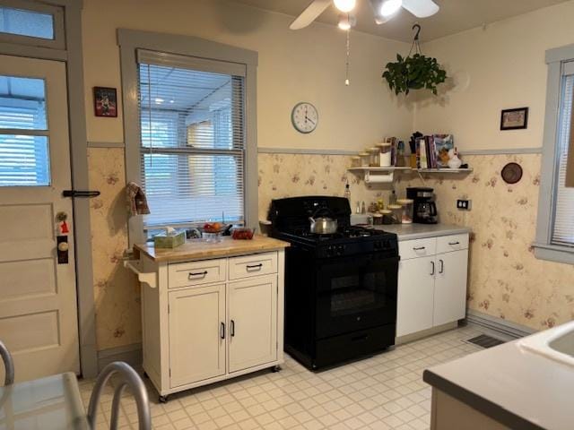 kitchen featuring ceiling fan, gas stove, and white cabinets