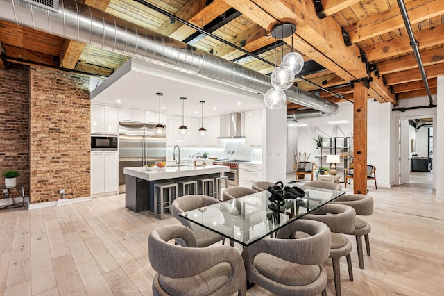 dining area featuring beamed ceiling, brick wall, wooden ceiling, and light wood-type flooring