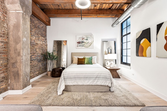 bedroom with brick wall, beam ceiling, multiple windows, and wooden ceiling