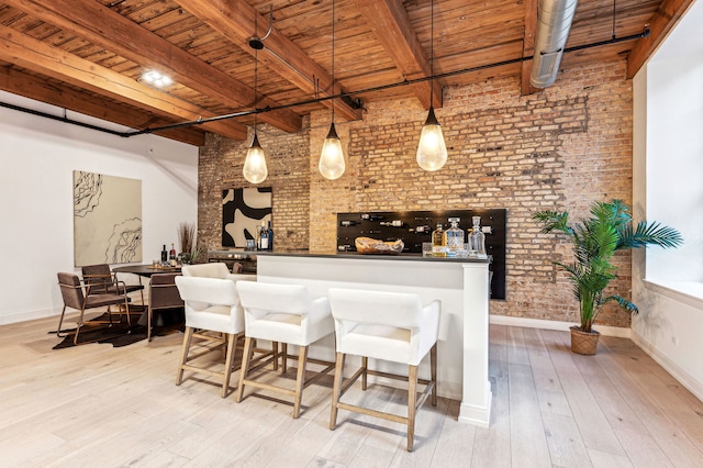 bar with wood ceiling, light hardwood / wood-style flooring, hanging light fixtures, beam ceiling, and brick wall