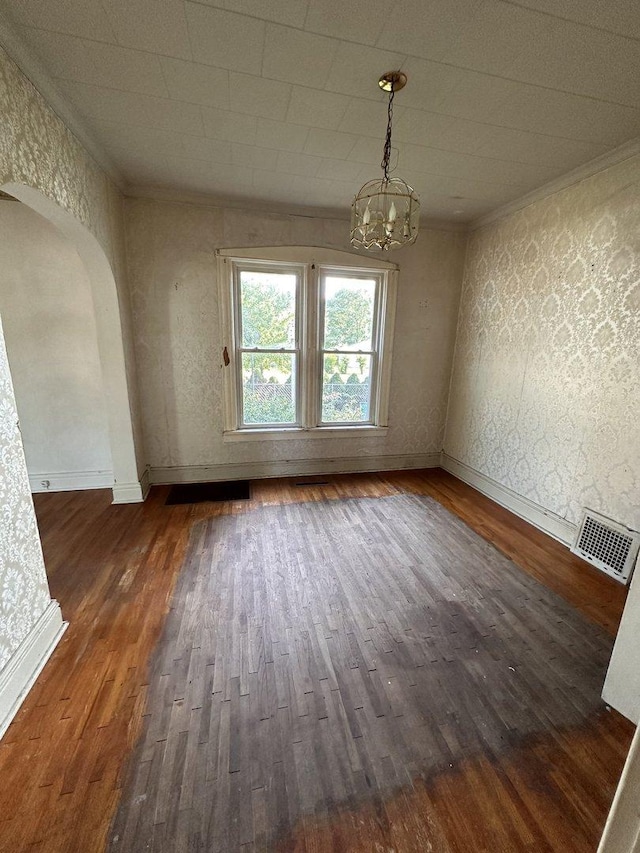 unfurnished dining area featuring crown molding, dark wood-type flooring, and a notable chandelier