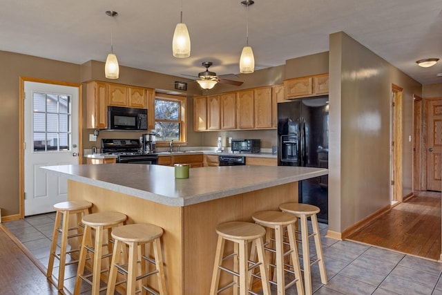 kitchen with light tile patterned floors, black appliances, and light brown cabinetry