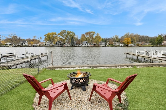 dock area with a water view, a yard, and a fire pit