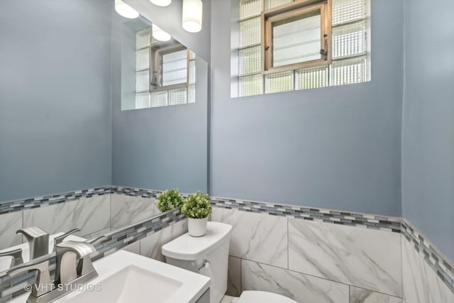 bathroom with sink, toilet, and tile walls