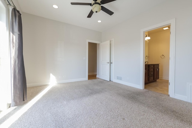 unfurnished bedroom featuring light carpet, connected bathroom, and ceiling fan