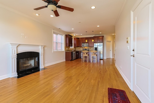 unfurnished living room featuring sink, light hardwood / wood-style flooring, ornamental molding, and ceiling fan