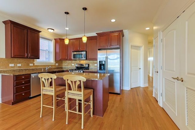 kitchen featuring light stone countertops, decorative light fixtures, stainless steel appliances, and a kitchen island