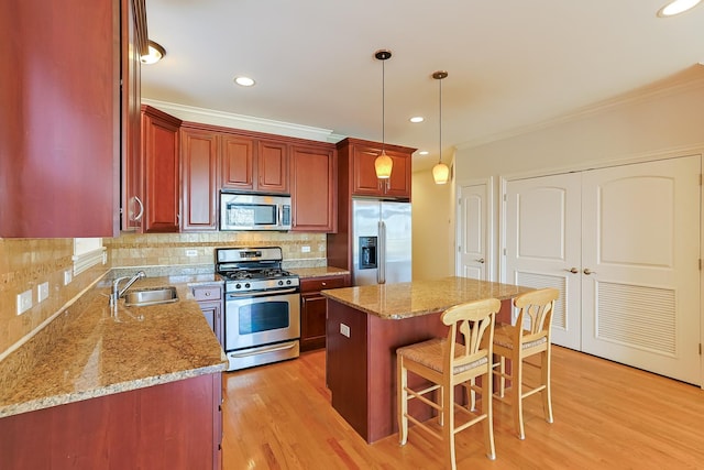 kitchen featuring sink, hanging light fixtures, a kitchen island, stainless steel appliances, and decorative backsplash