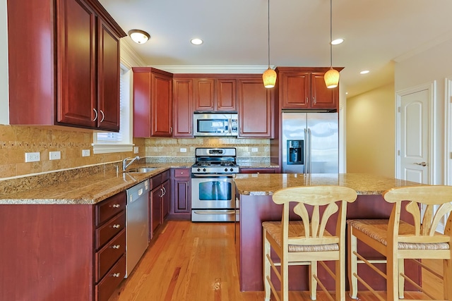 kitchen featuring appliances with stainless steel finishes, decorative light fixtures, light stone countertops, and sink