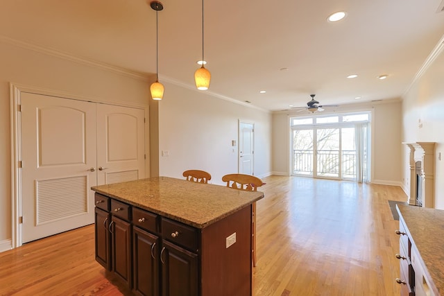 kitchen featuring pendant lighting, dark brown cabinets, ornamental molding, and light wood-type flooring