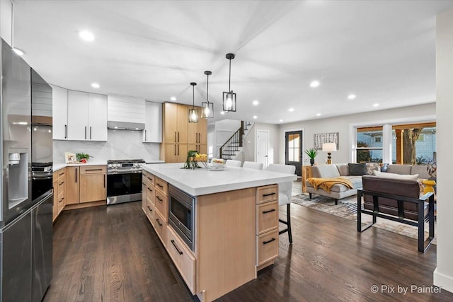 kitchen featuring dark wood-style floors, light brown cabinets, stainless steel appliances, and open floor plan